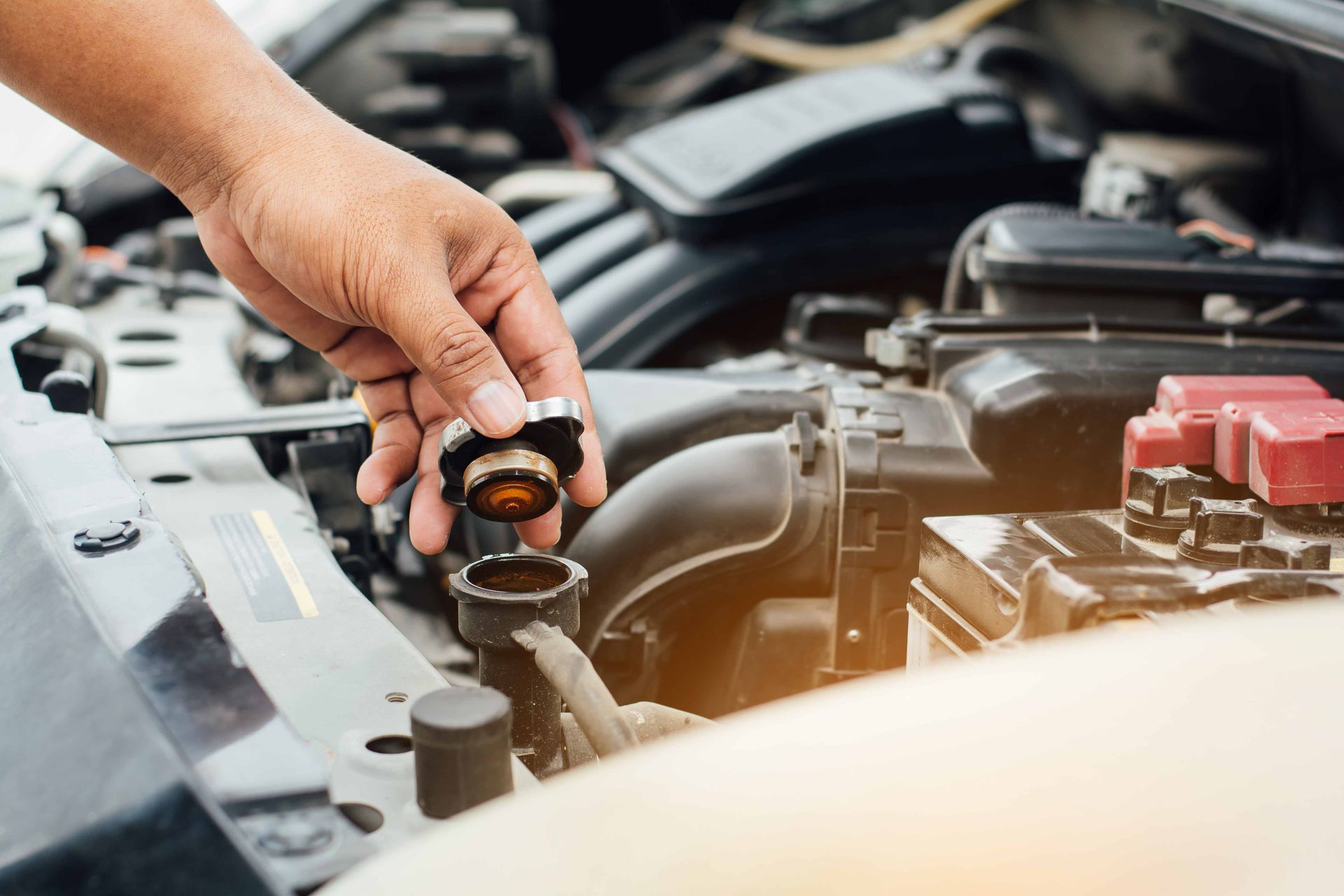 a person is holding a radiator cap over a car radiator