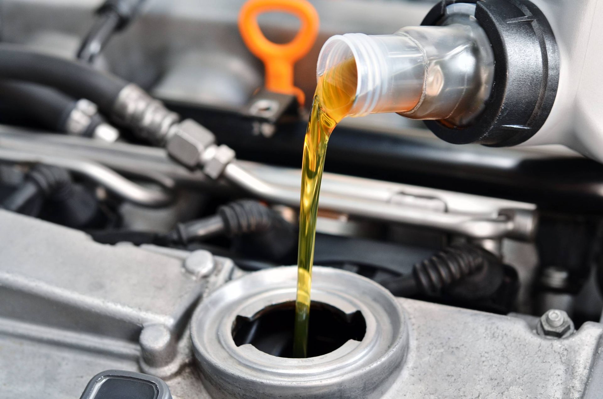 a bottle of oil is being poured into a car engine