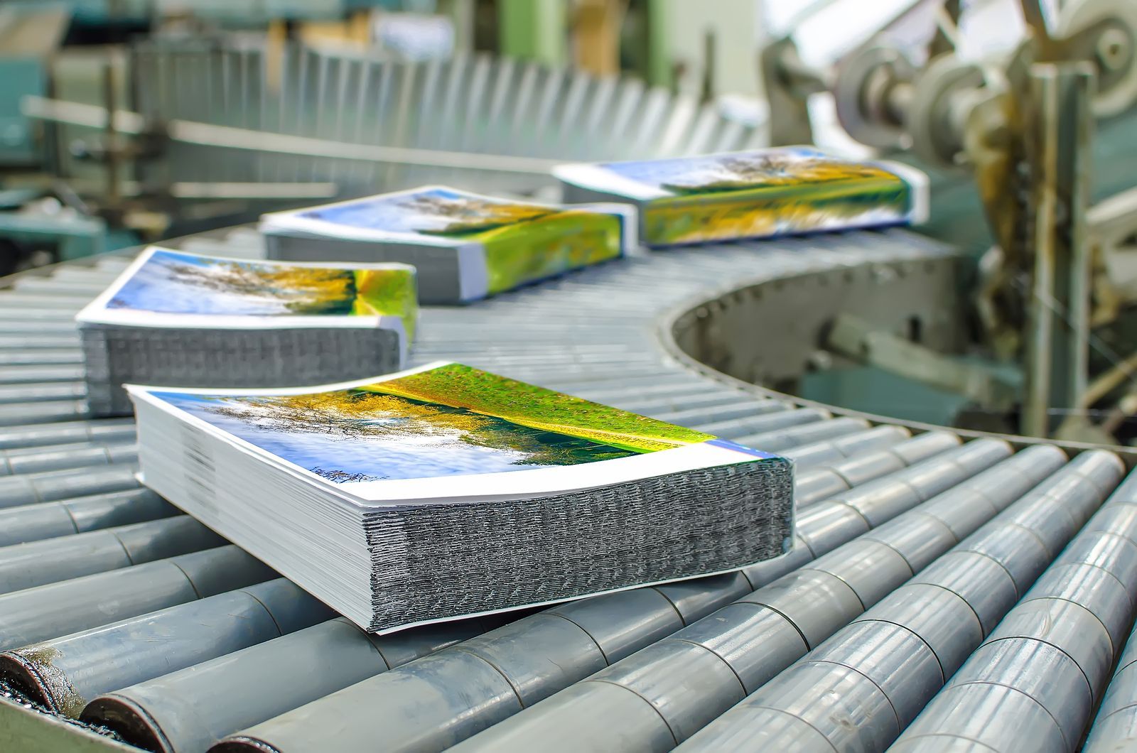 Stacks of printed brochures move along a factory conveyor belt.