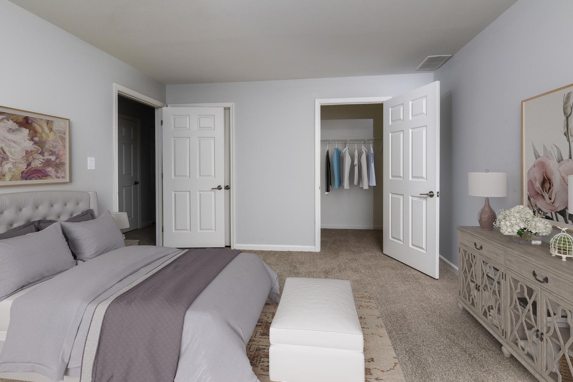 Bedroom in an apartment with a tufted headboard, gray bedding, and an open closet.