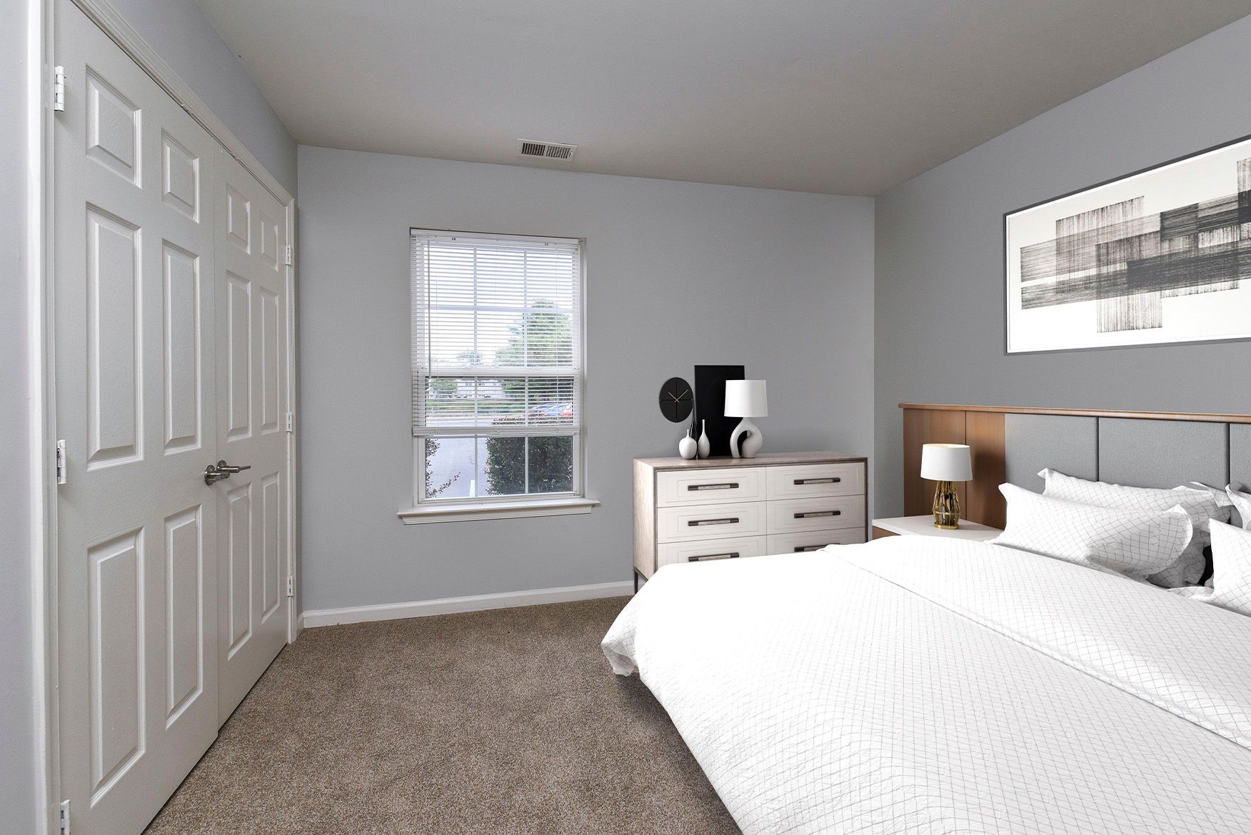 Bedroom in an apartment with a large bed, dresser, and window.