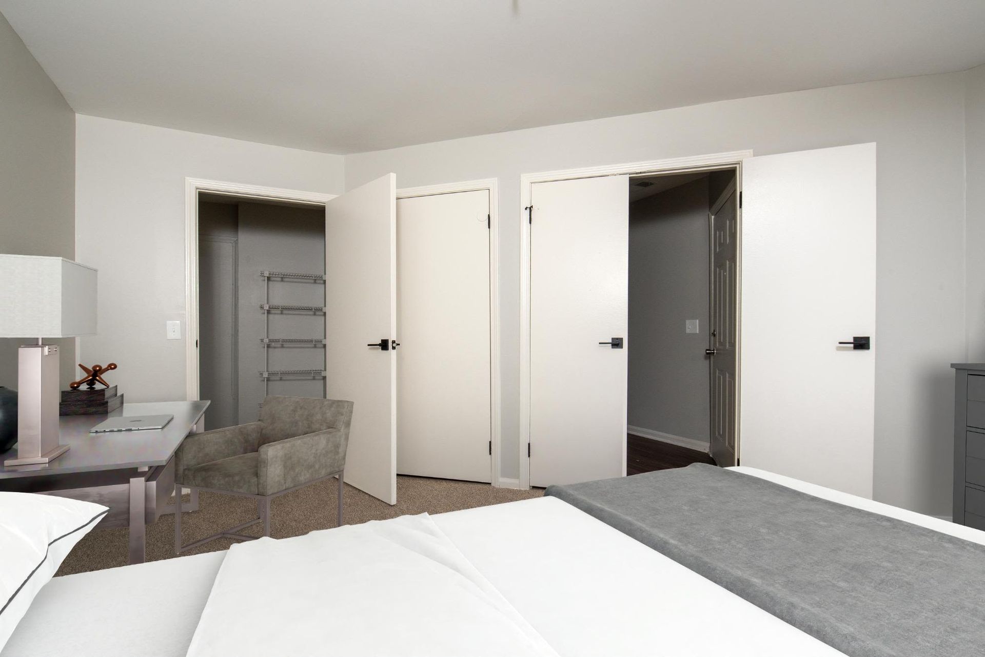 Furnished bedroom with bed, desk, chair, and open closet.