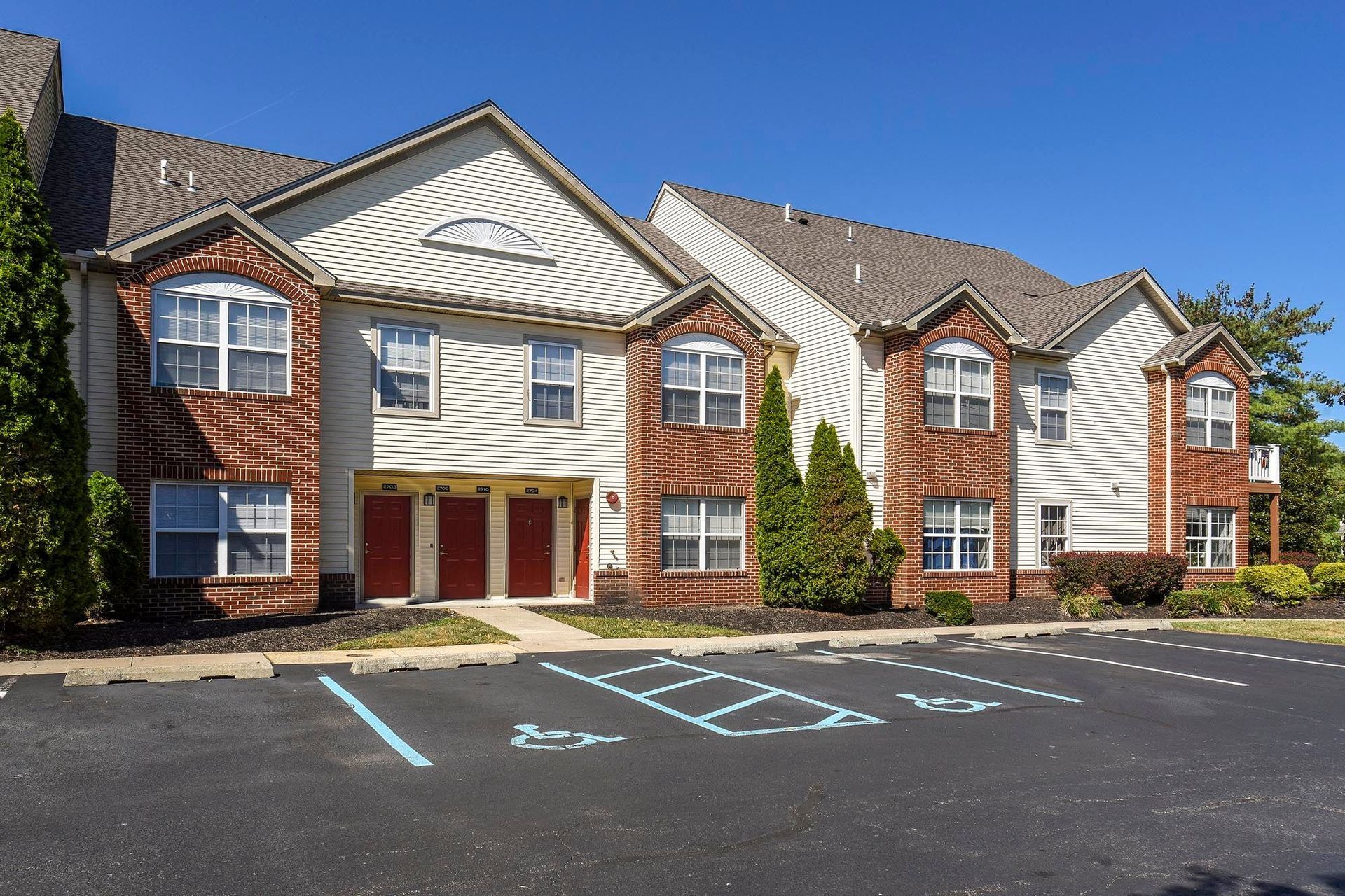 Exterior view of a multi-building apartment complex with handicap parking in the foreground.