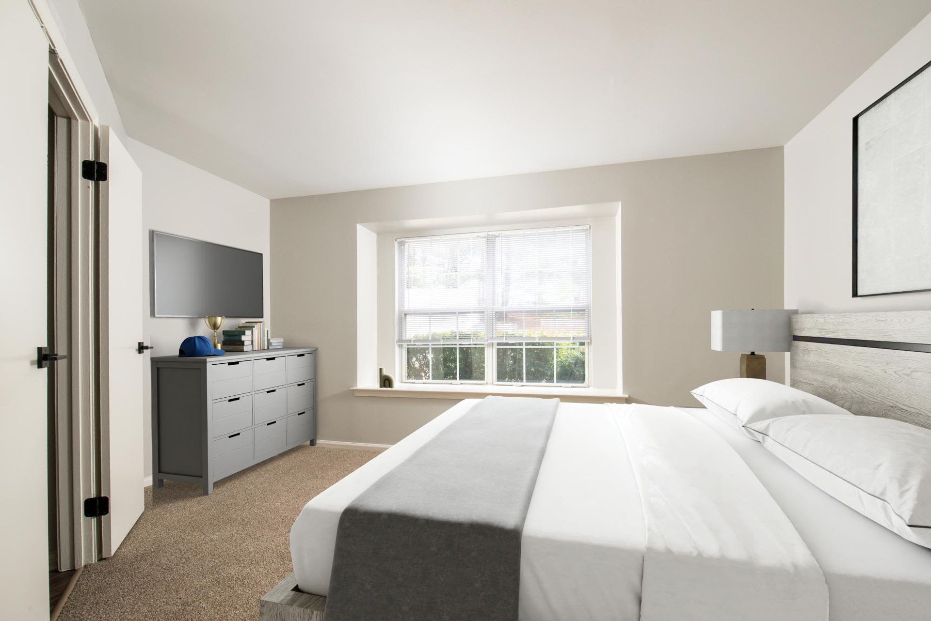 Bright bedroom with a large window, gray dresser, wall-mounted TV, and a neatly made bed.
