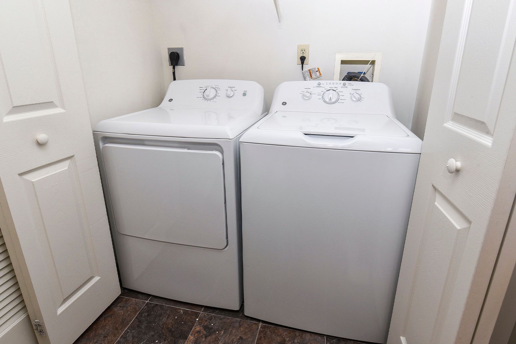 White washer and dryer in a small apartment laundry closet.