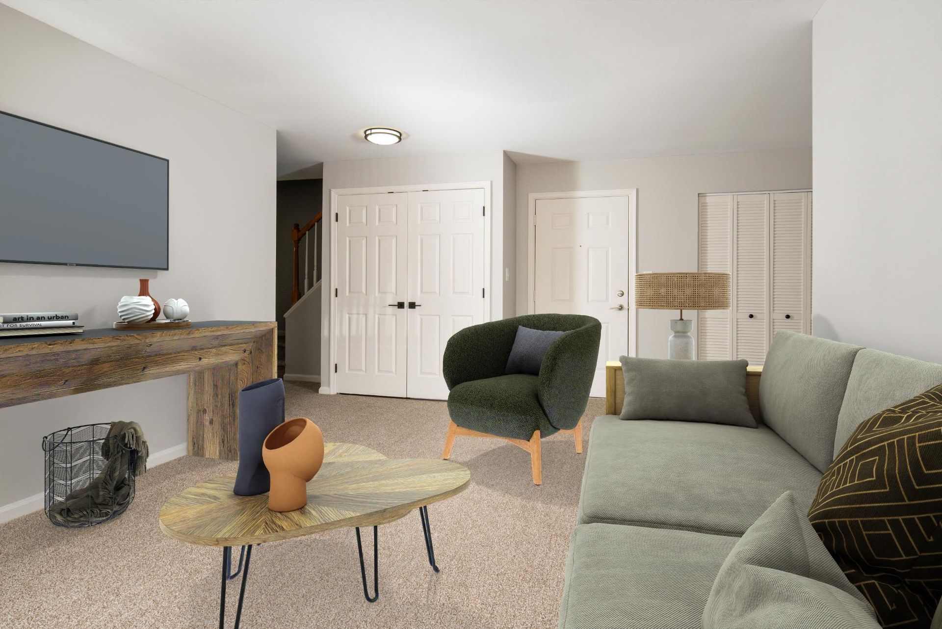 Living room in an apartment with a gray sofa, green accent chair, wood coffee table, and mounted TV.