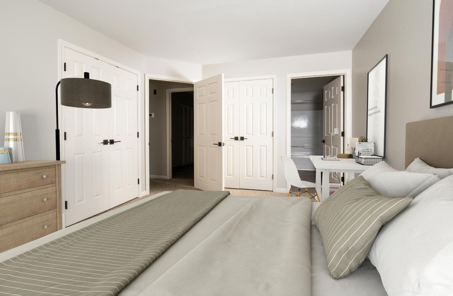 Bedroom in an apartment with a bed, dresser, desk, and double closet doors.