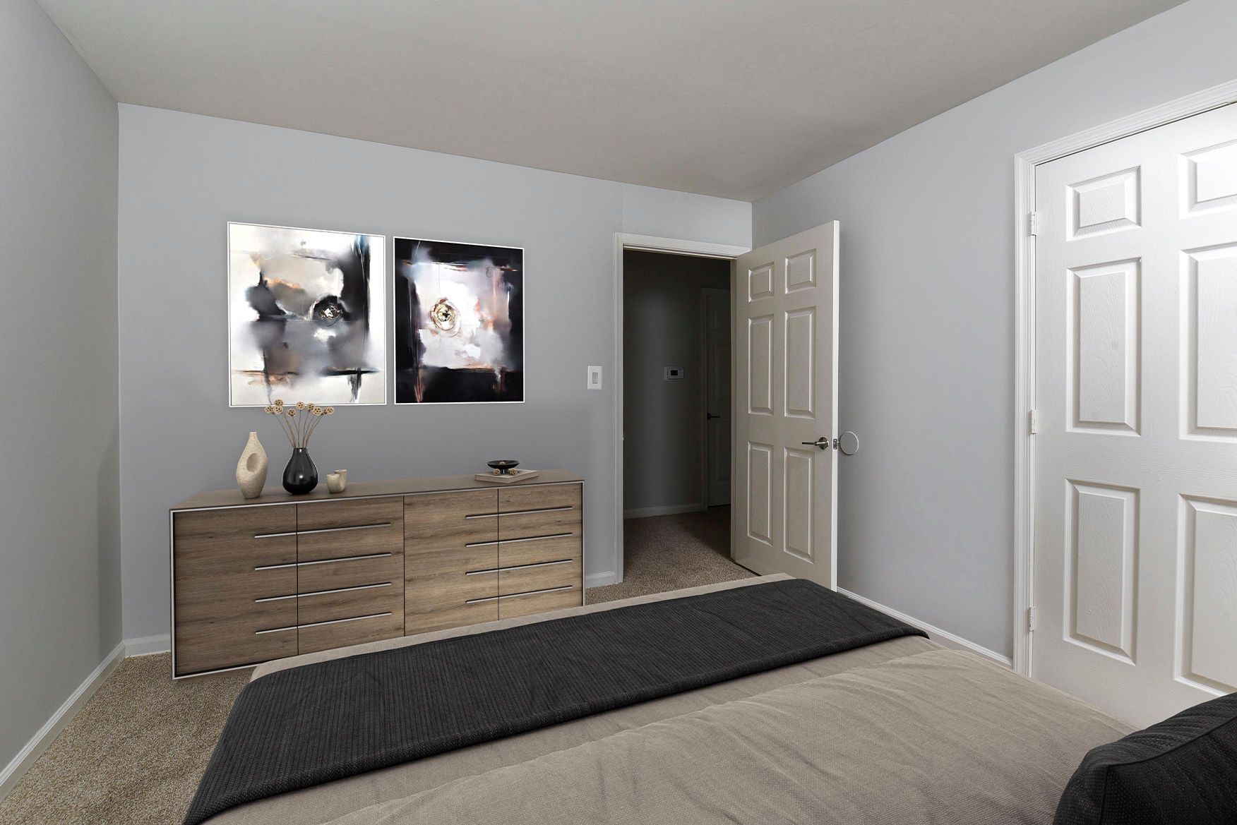 Bedroom interior with a wooden dresser, two abstract art prints, and neutral gray walls.