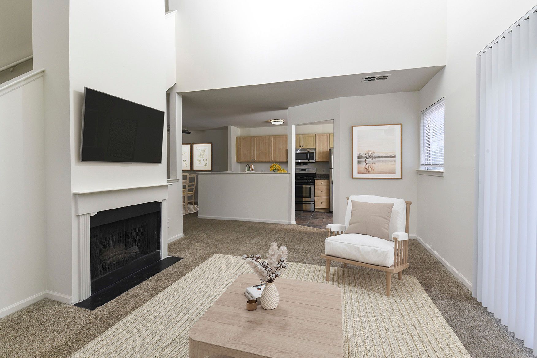 Living room in an apartment with a fireplace, mounted TV, and open kitchen.