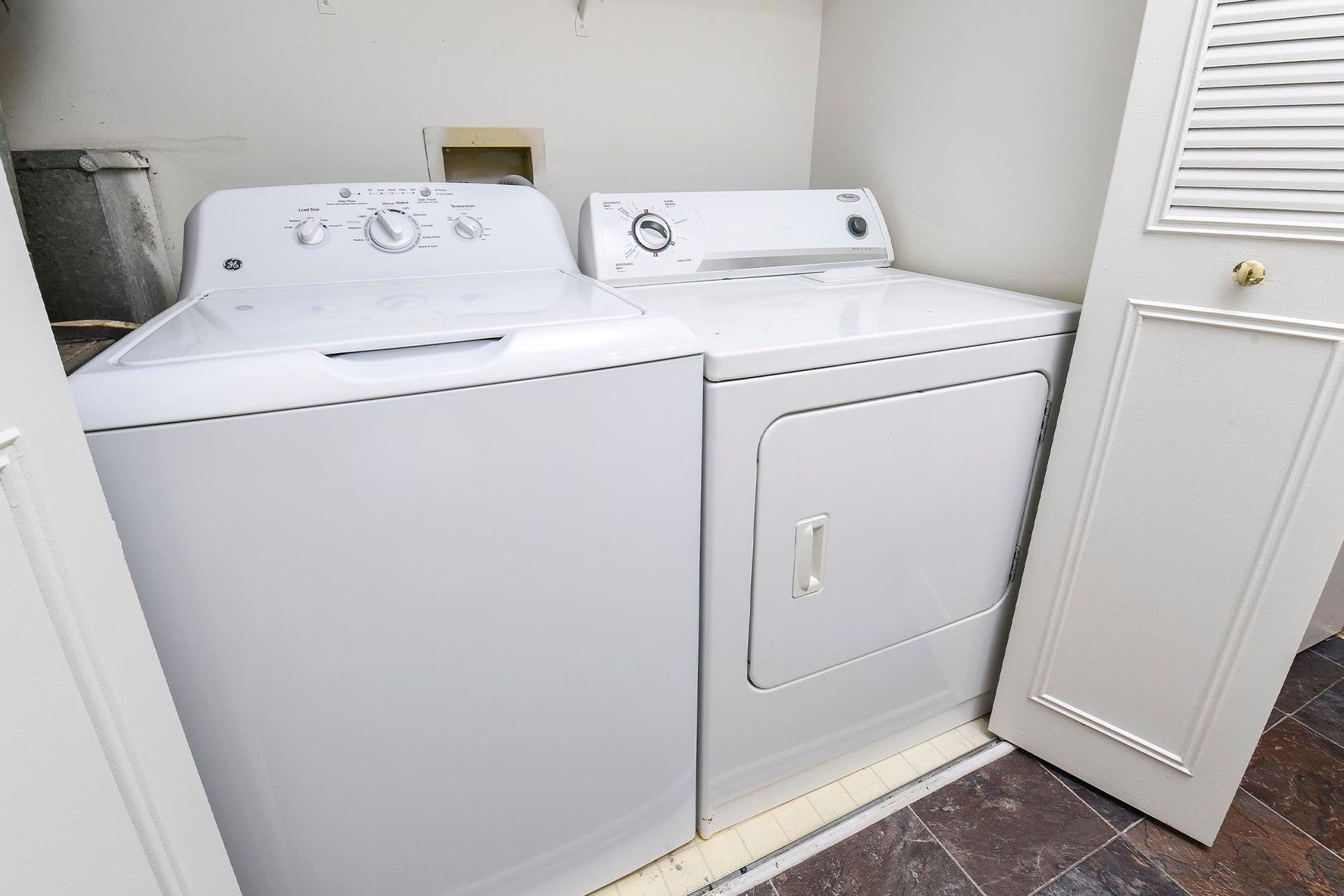 White top-load washing machine and front-loading dryer in a compact laundry closet.
