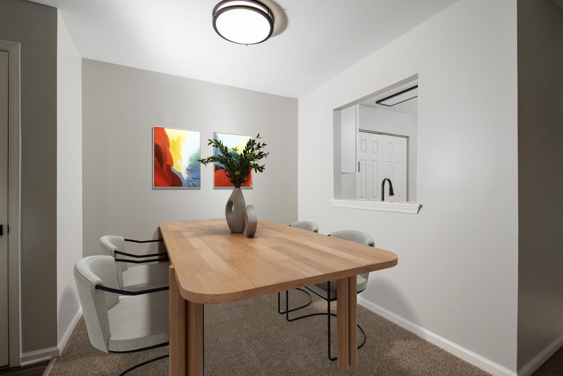 Dining area with a wooden table, beige chairs, and a pass-through to the kitchen.
