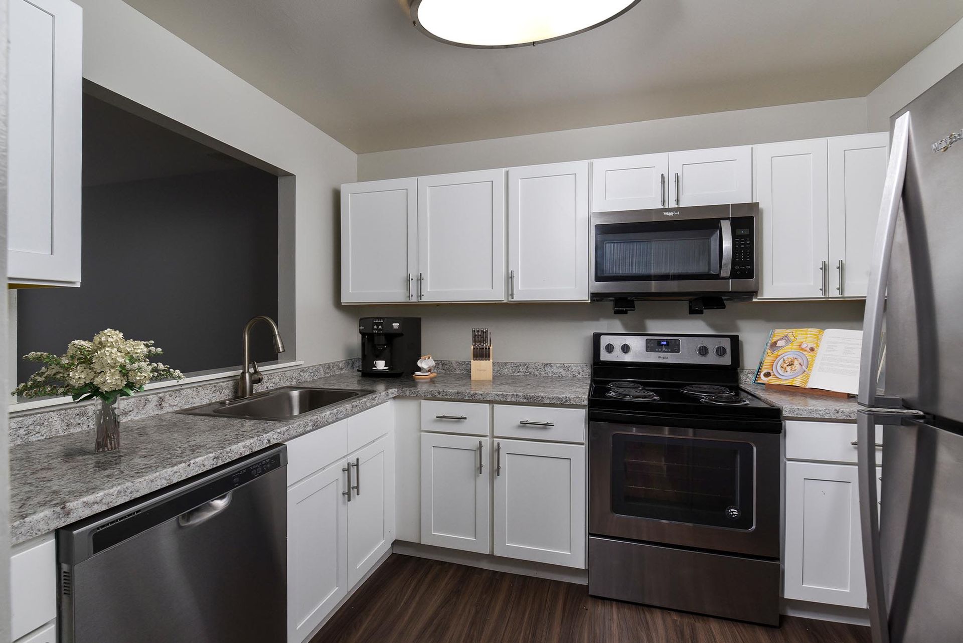 Modern kitchen with white cabinets, granite countertops, and stainless steel appliances.