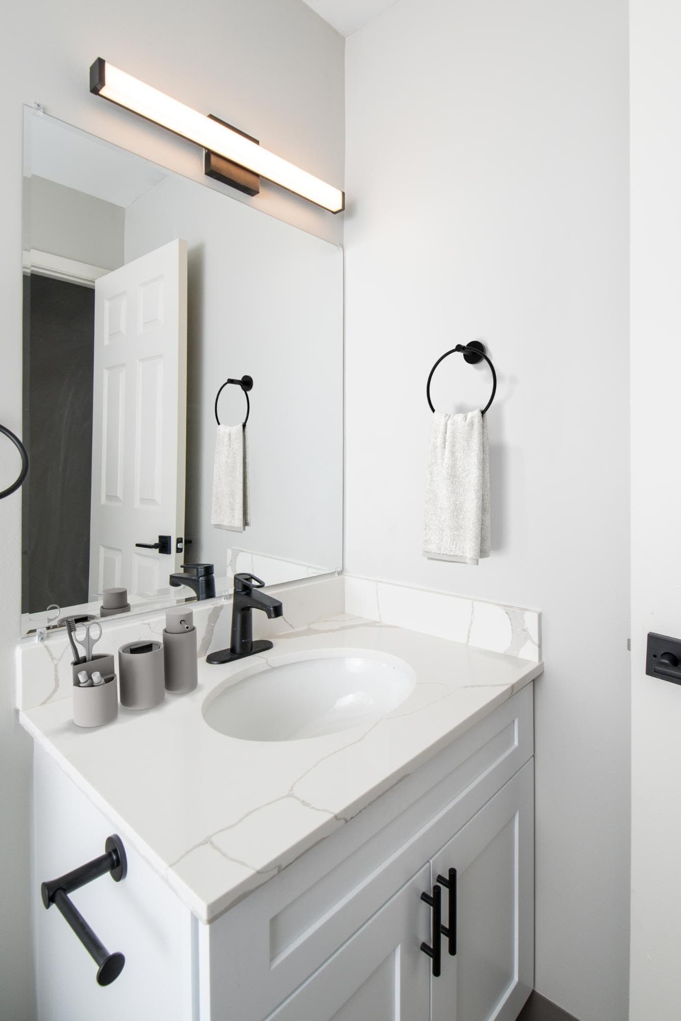 White bathroom vanity with marble countertop, sink, and black faucet.
