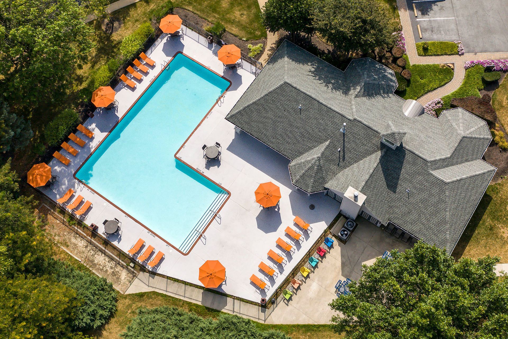 Aerial view of a residential community pool with orange umbrellas and lounge chairs