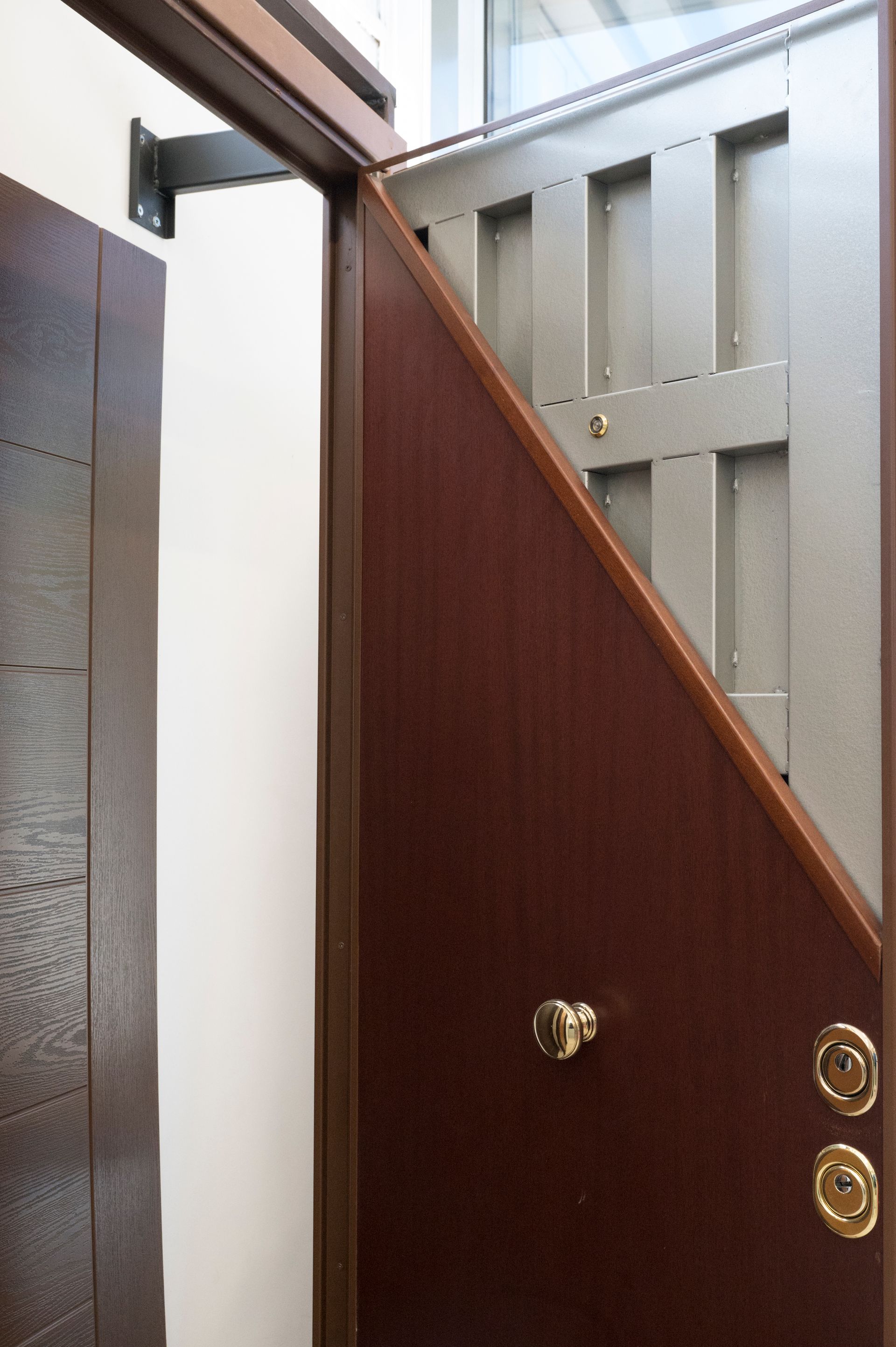 Porta marrone parzialmente aperta con pomello in ottone in uno stretto corridoio interno