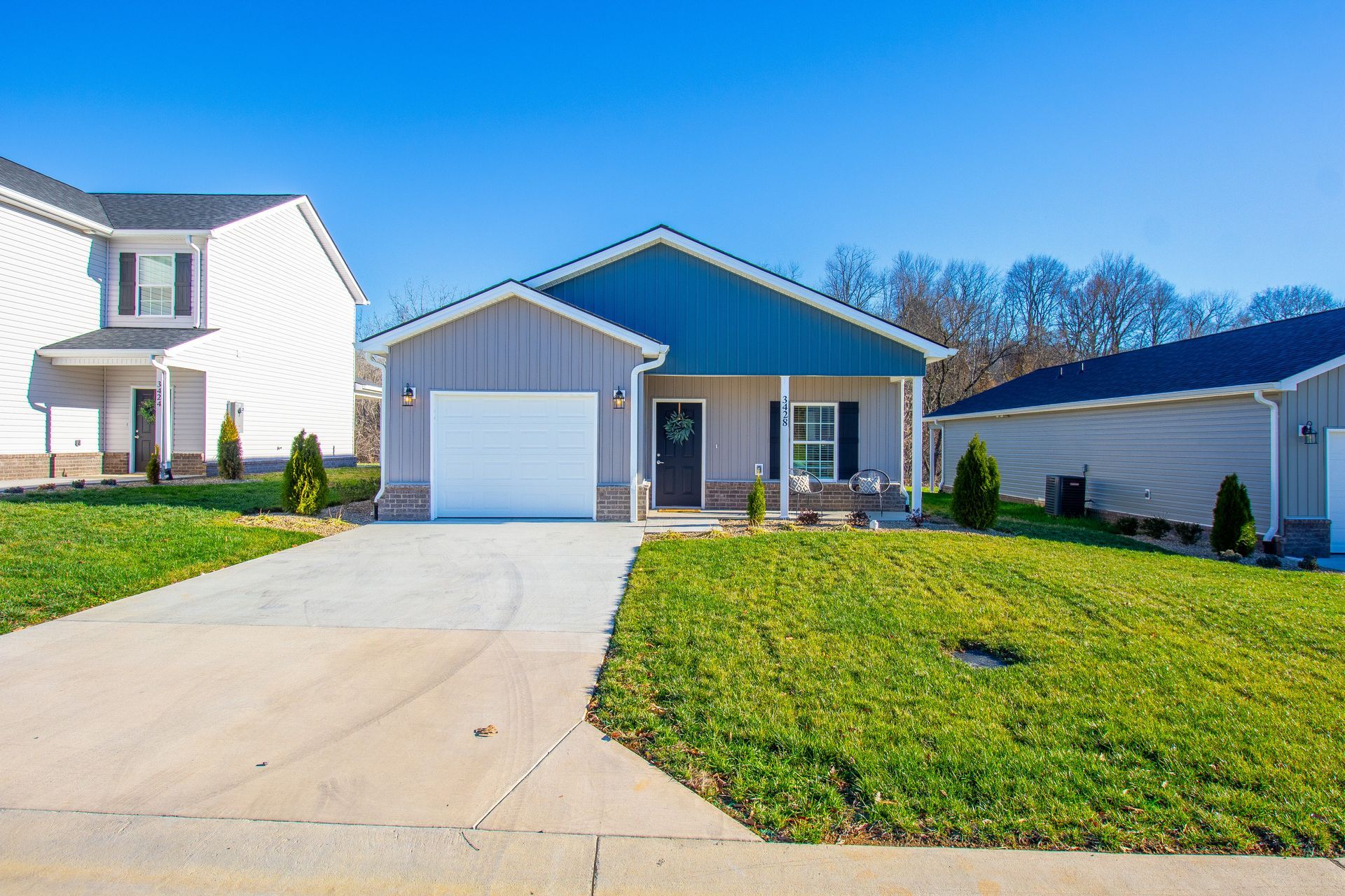 A house with a green roof and a white garage door is for sale in a residential area.