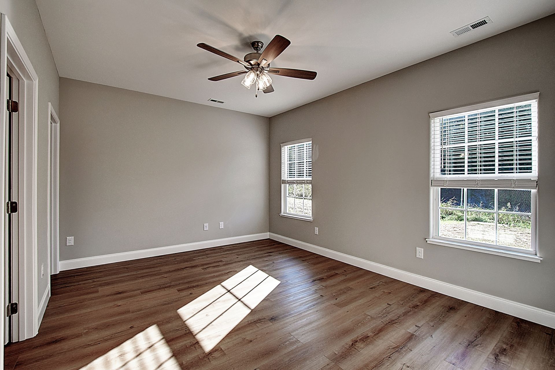 An empty bedroom with hardwood floors and a ceiling fan.