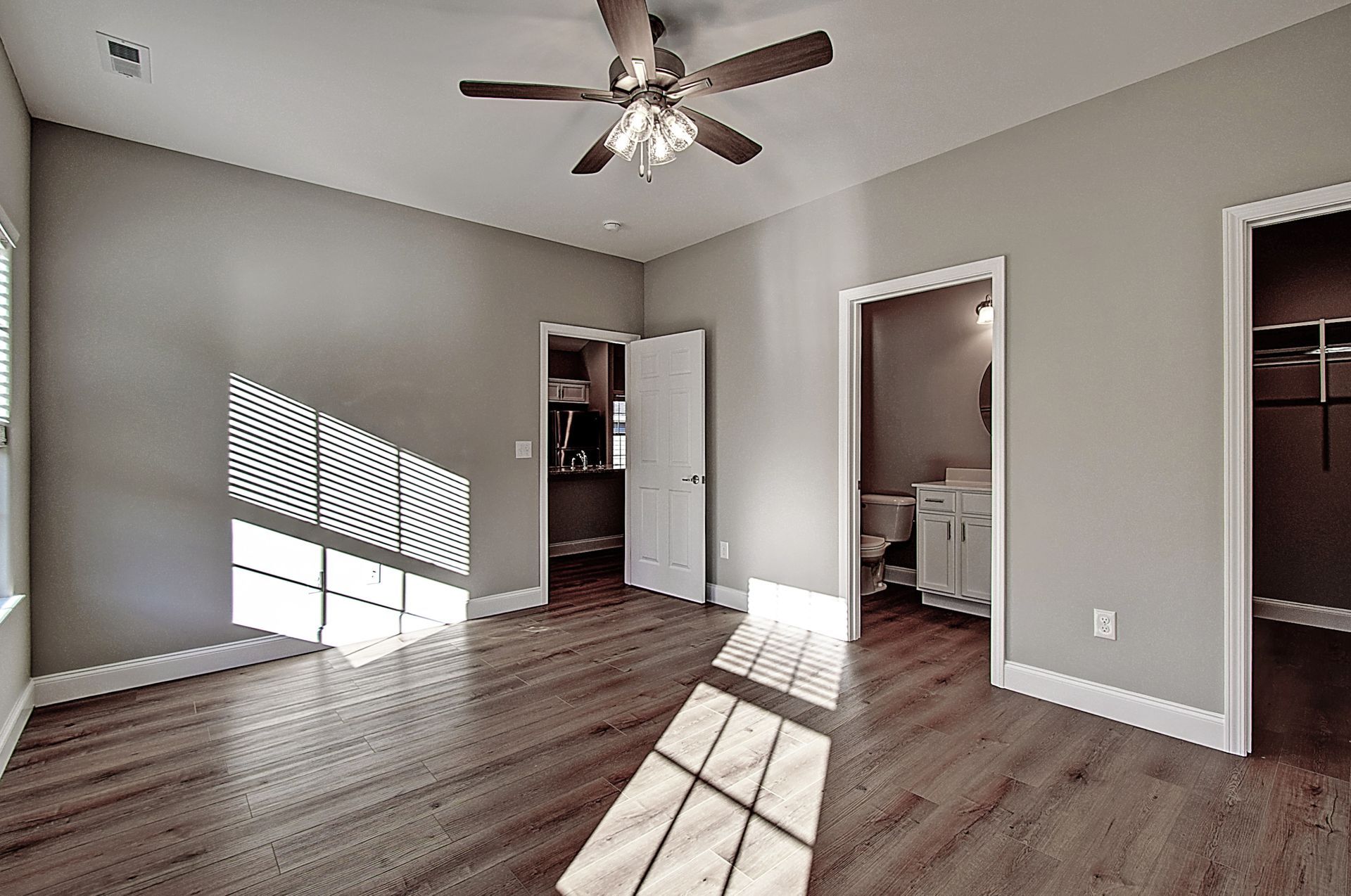 An empty bedroom with hardwood floors and a ceiling fan.