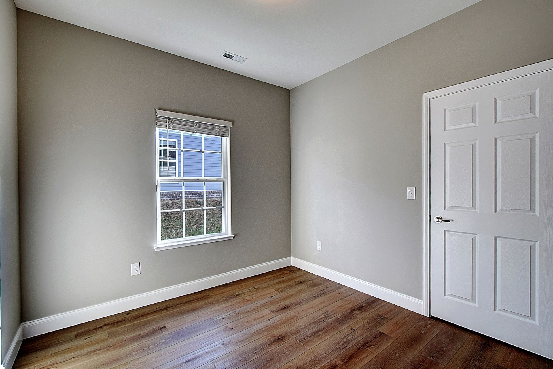 An empty bedroom with hardwood floors and a window