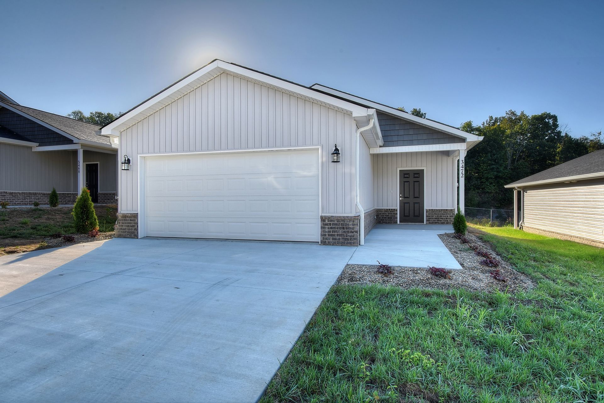 A white house with a garage and a concrete driveway