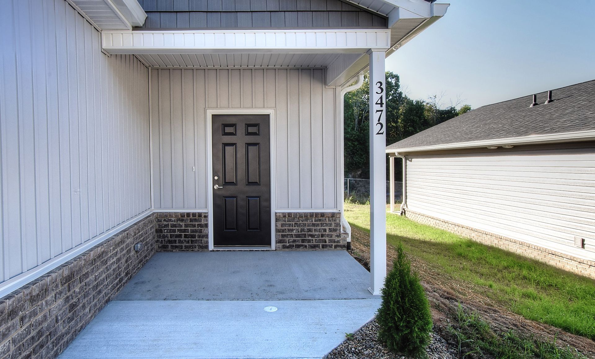 A white house with a black door and a porch.