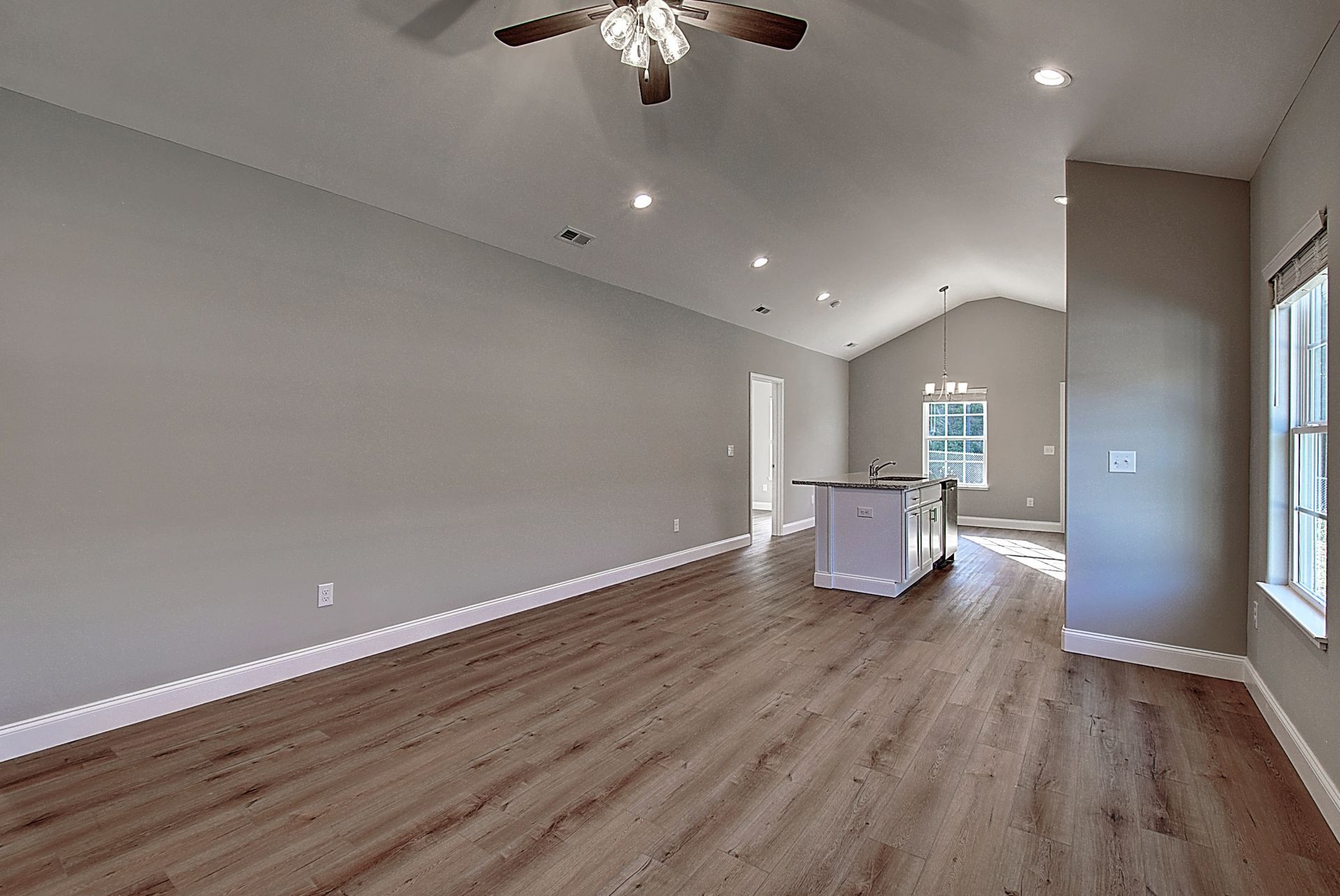 An empty living room with hardwood floors and a ceiling fan.