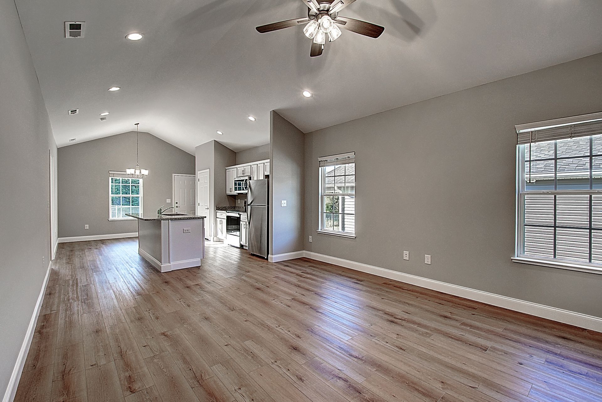 An empty living room with hardwood floors and a ceiling fan.