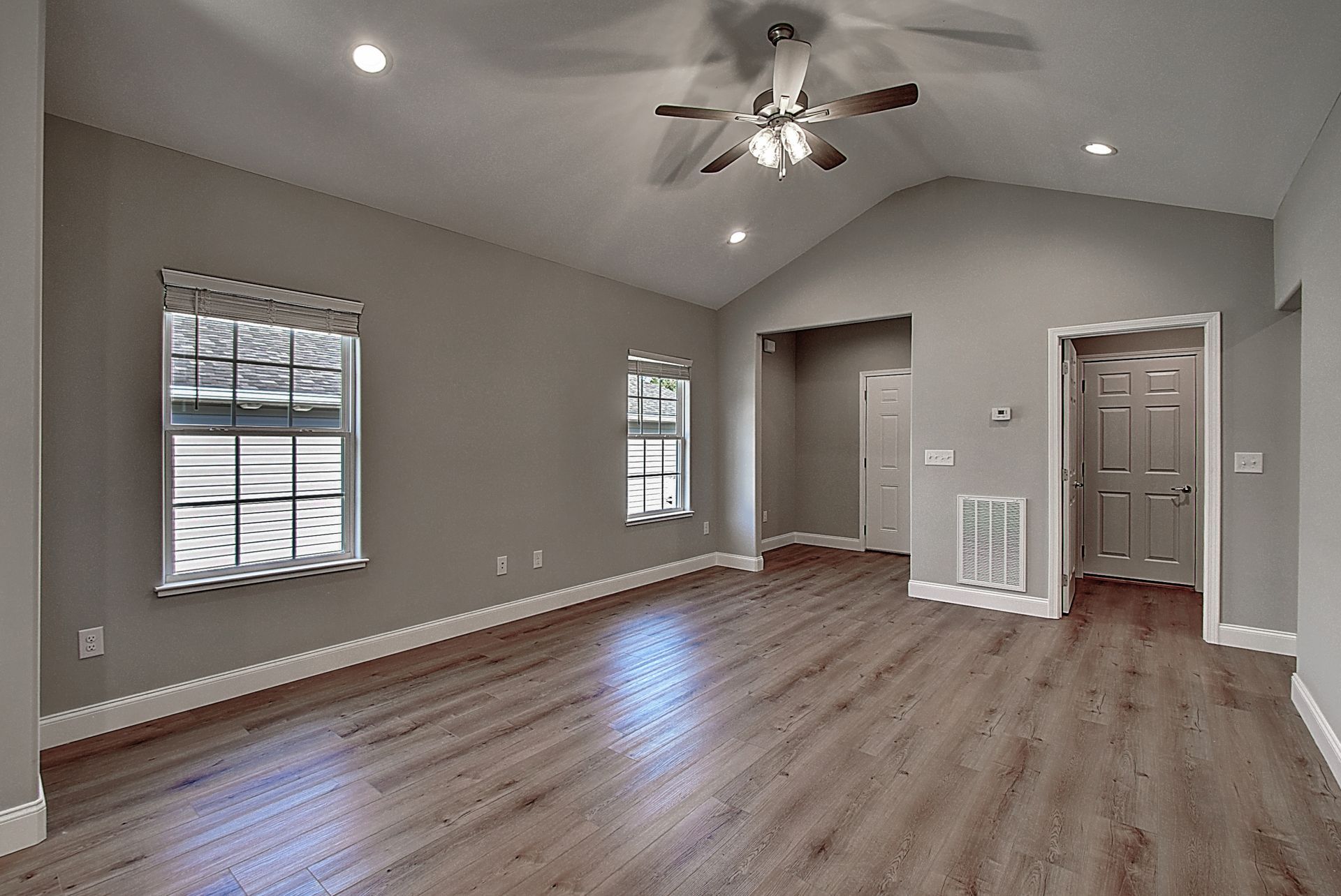 An empty living room with hardwood floors and a ceiling fan.