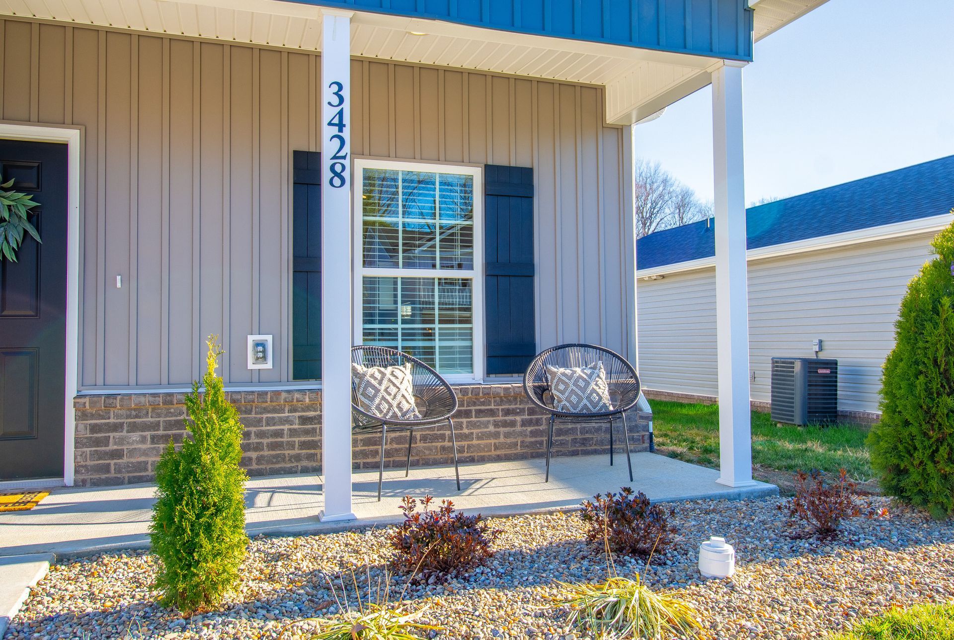 A house with a porch and chairs in front of it.
