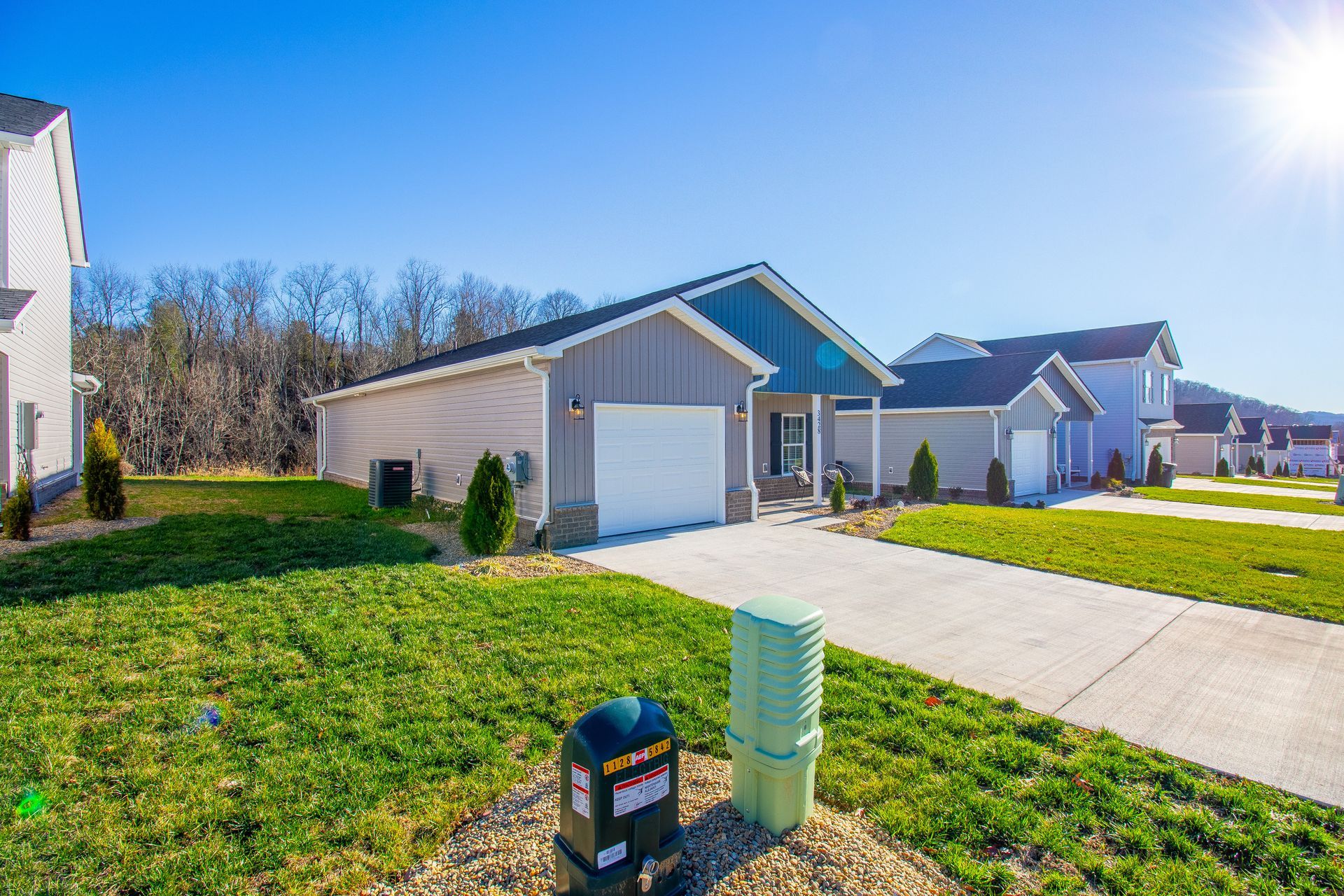 A house with a green roof and a white garage door is in a residential neighborhood.