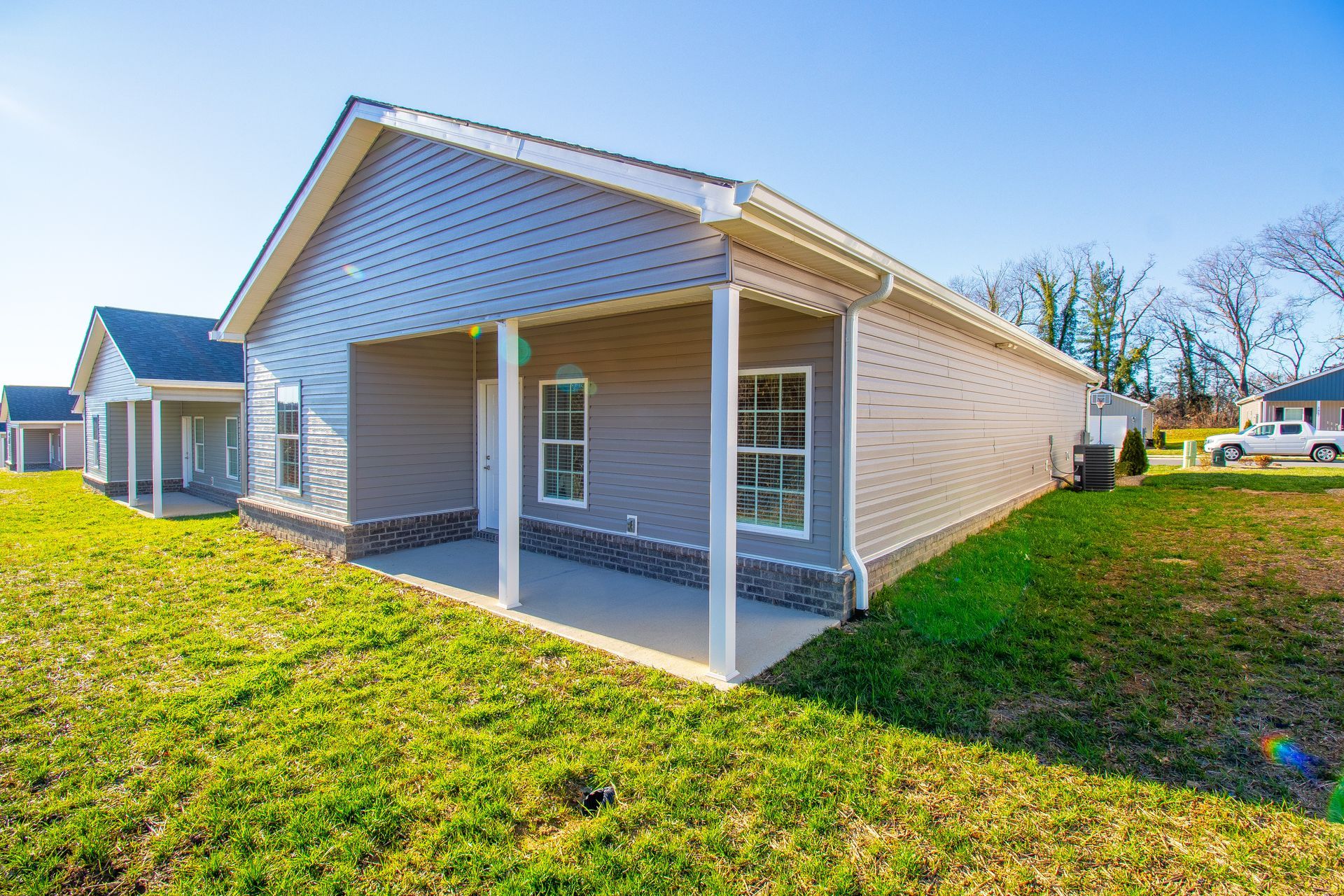 A house with a porch is sitting on top of a lush green field.