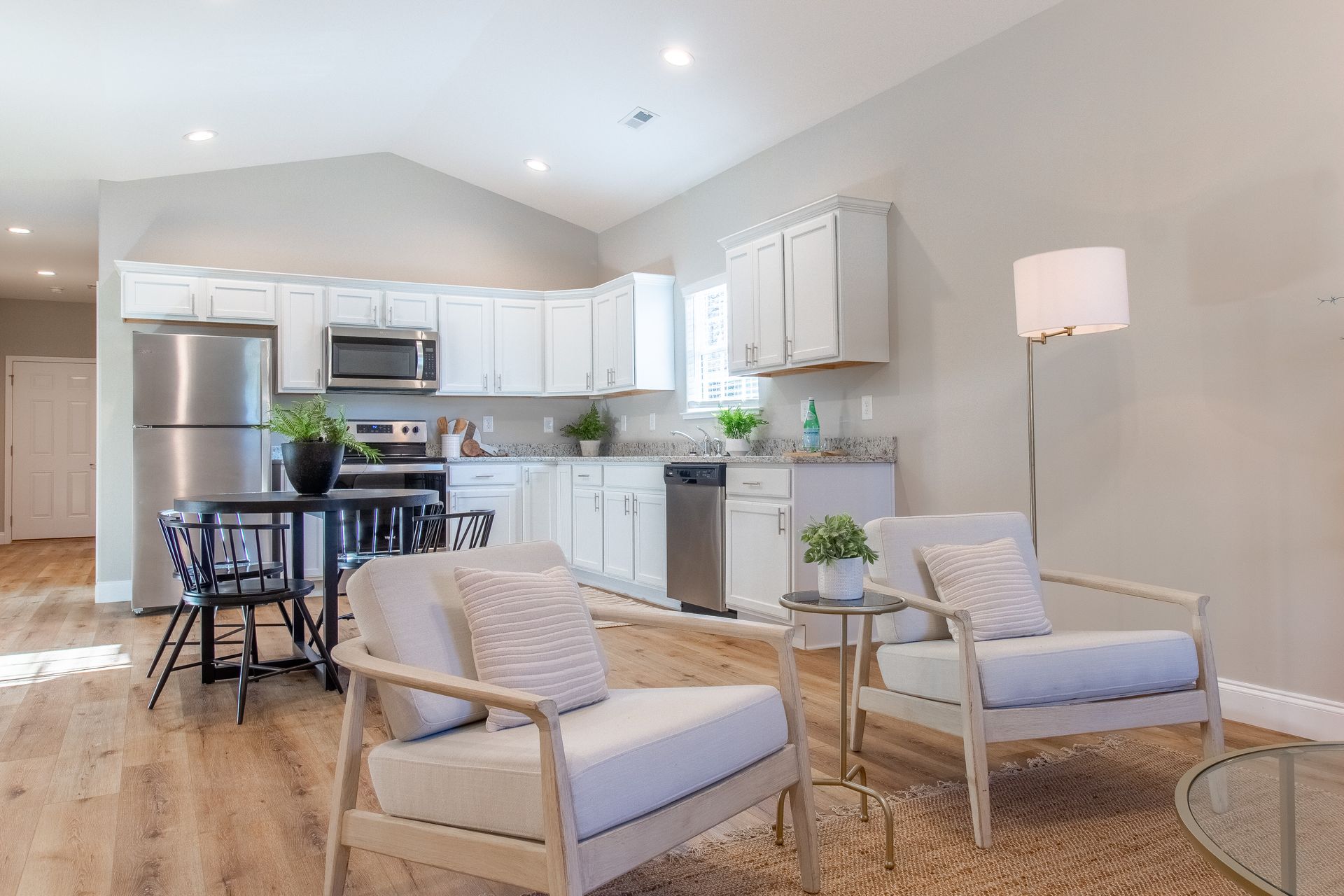 A living room with two chairs , a table and a refrigerator.