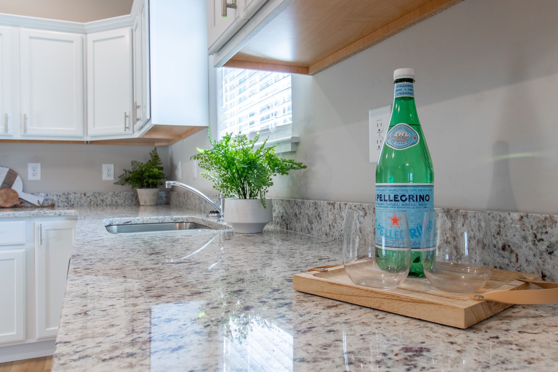 A kitchen counter with a bottle of water and a glass on it.