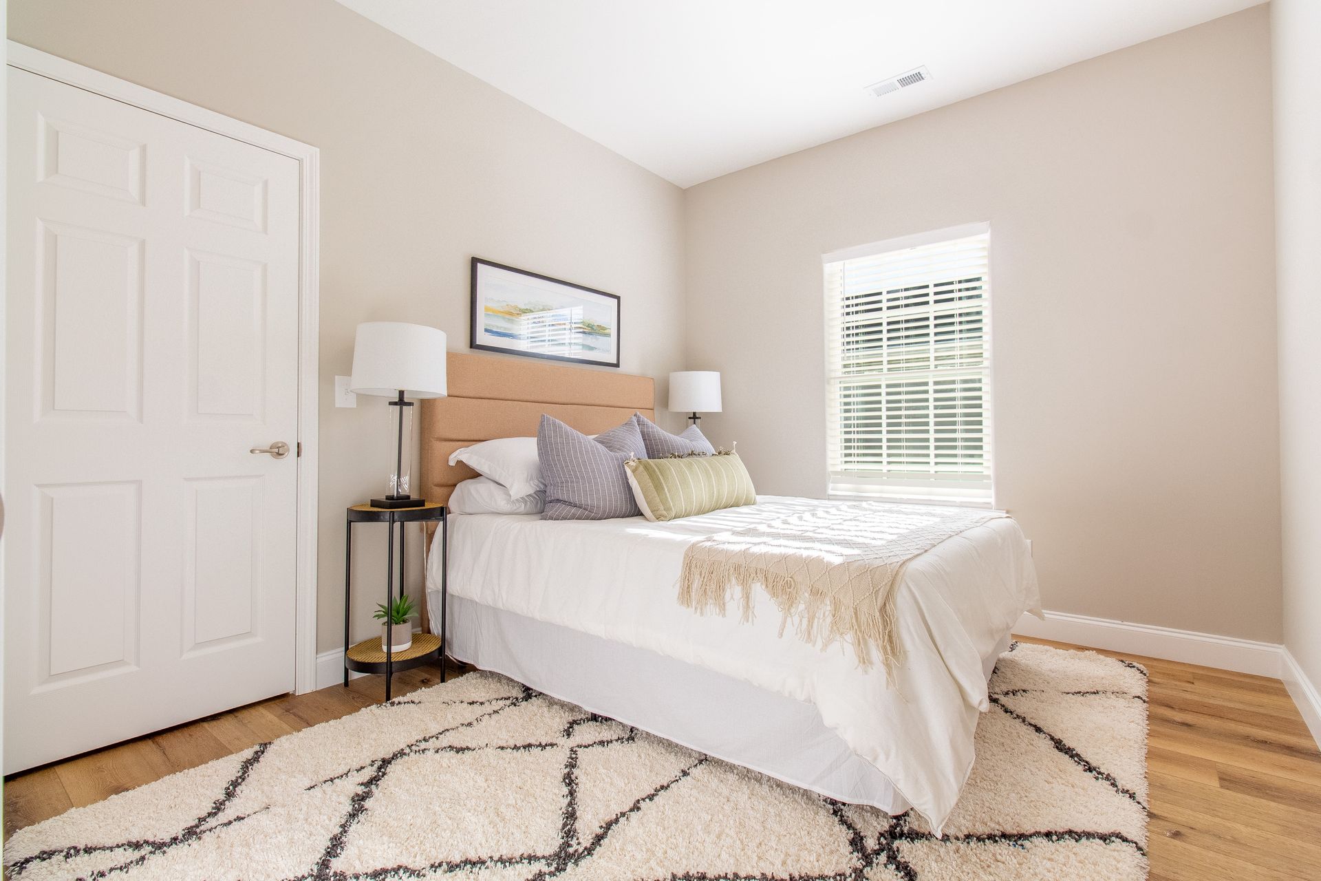 A bedroom with a bed , nightstand , lamp and rug.