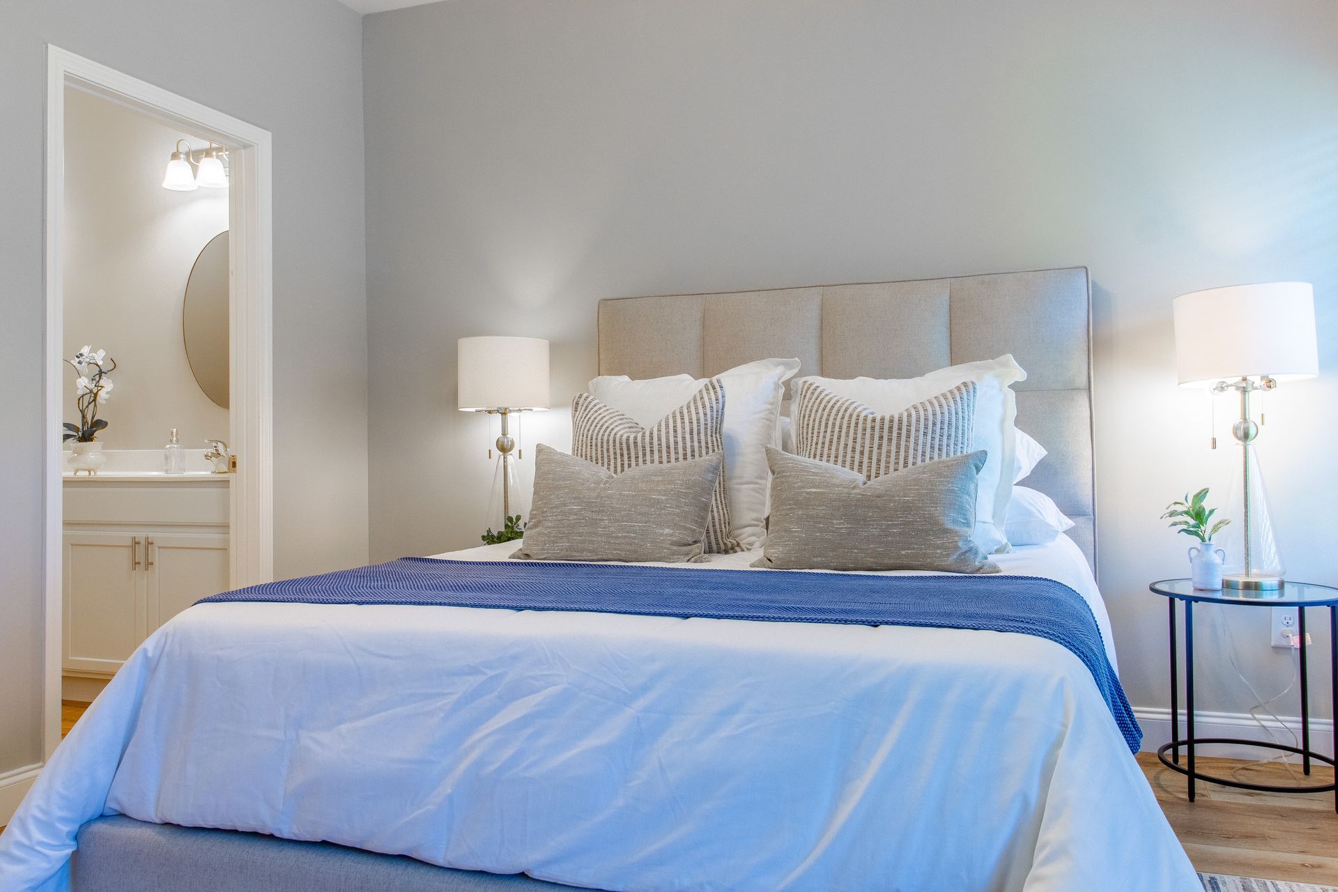 A bedroom with a bed , nightstand , lamps and a bathroom.