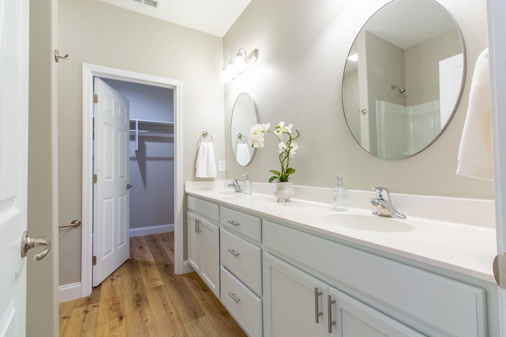 A bathroom with two sinks , two mirrors and a walk in closet.