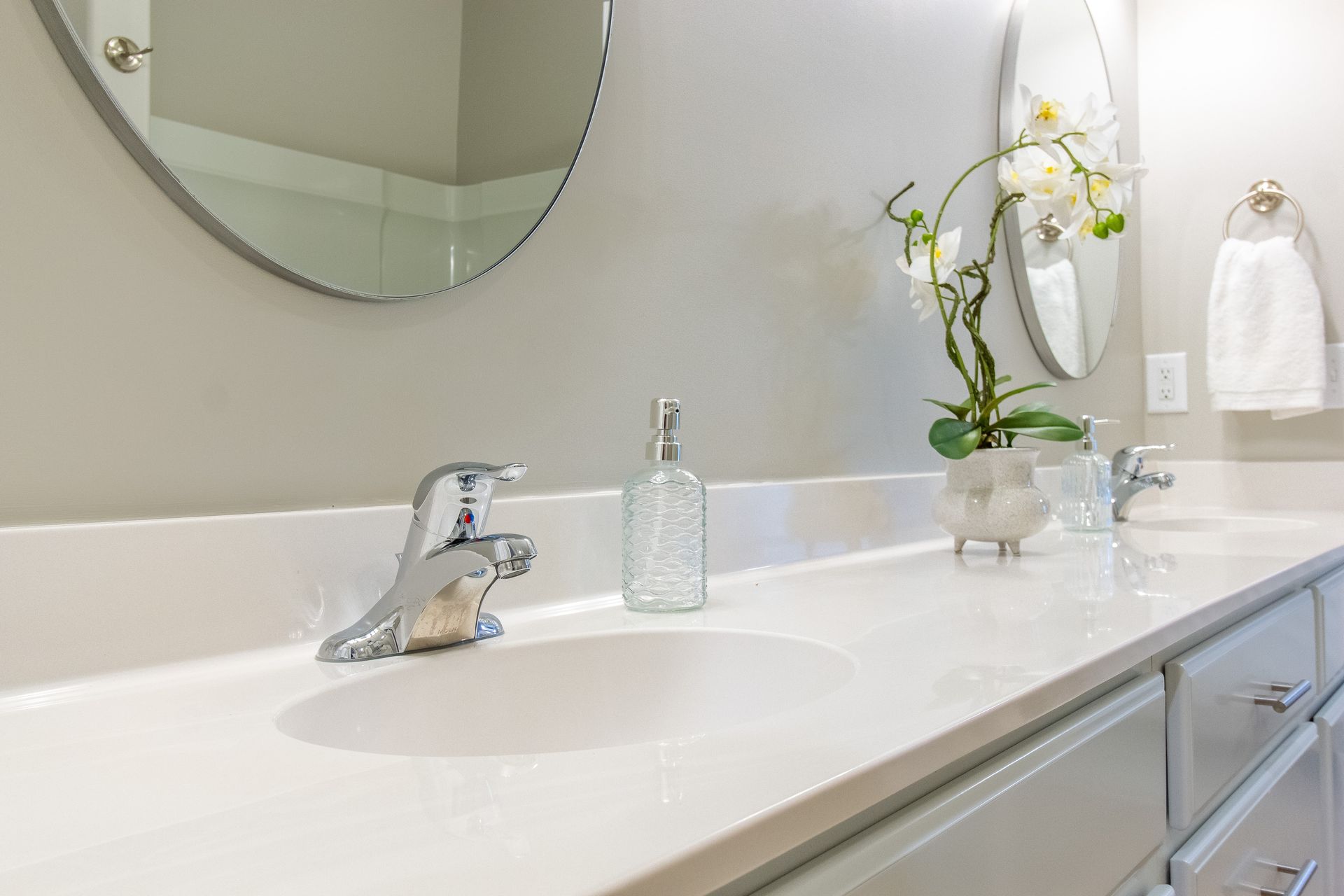 A bathroom with two sinks and a round mirror.