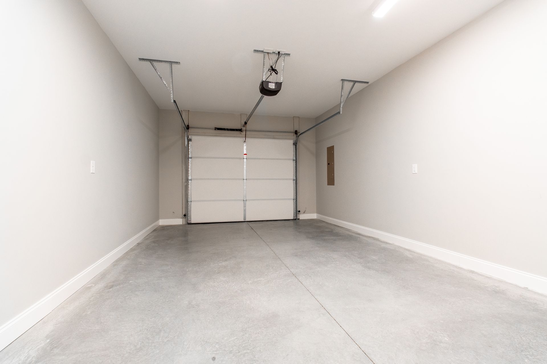 An empty garage with a garage door open and a garage door opener.