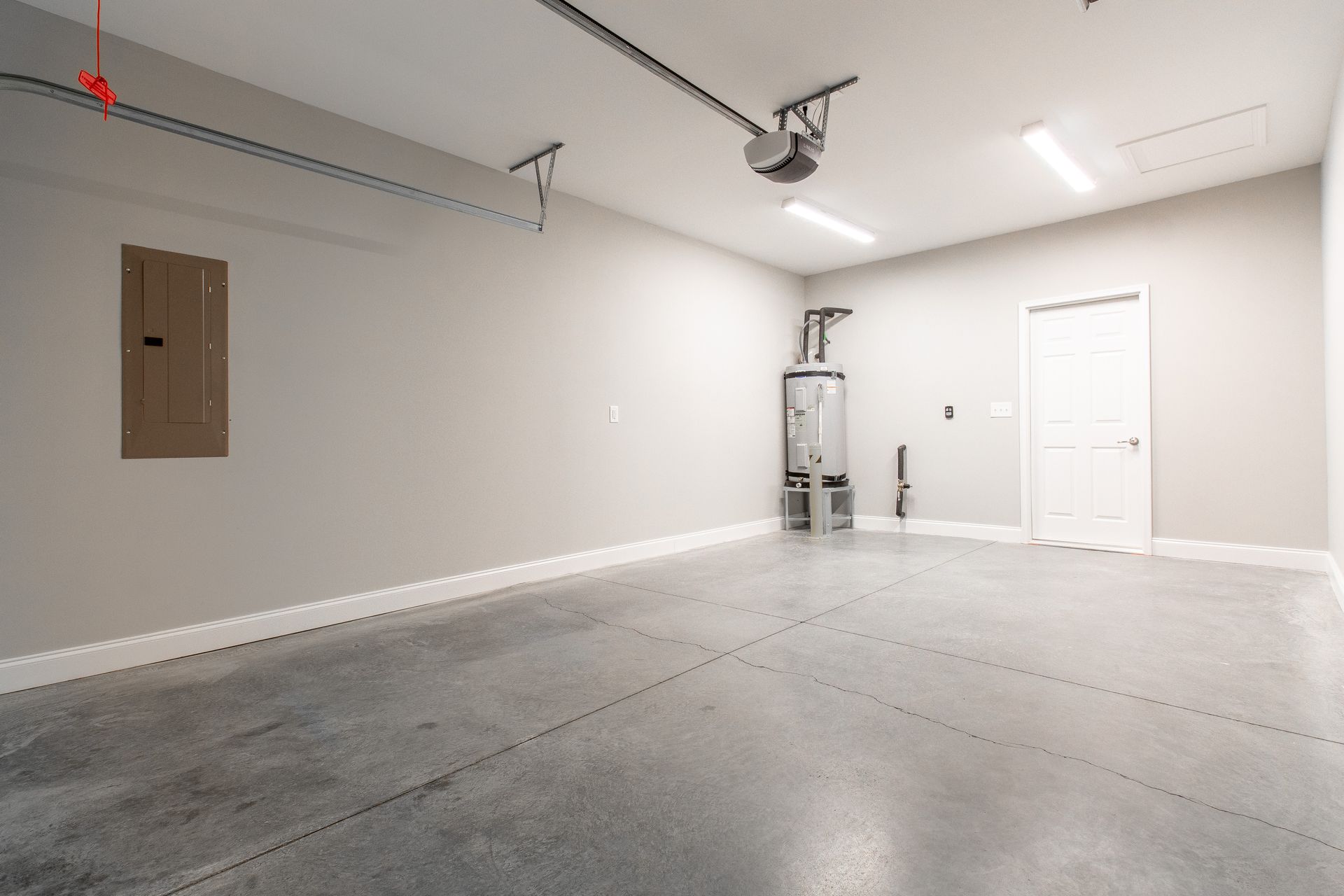 An empty garage with a concrete floor and a garage door opener.
