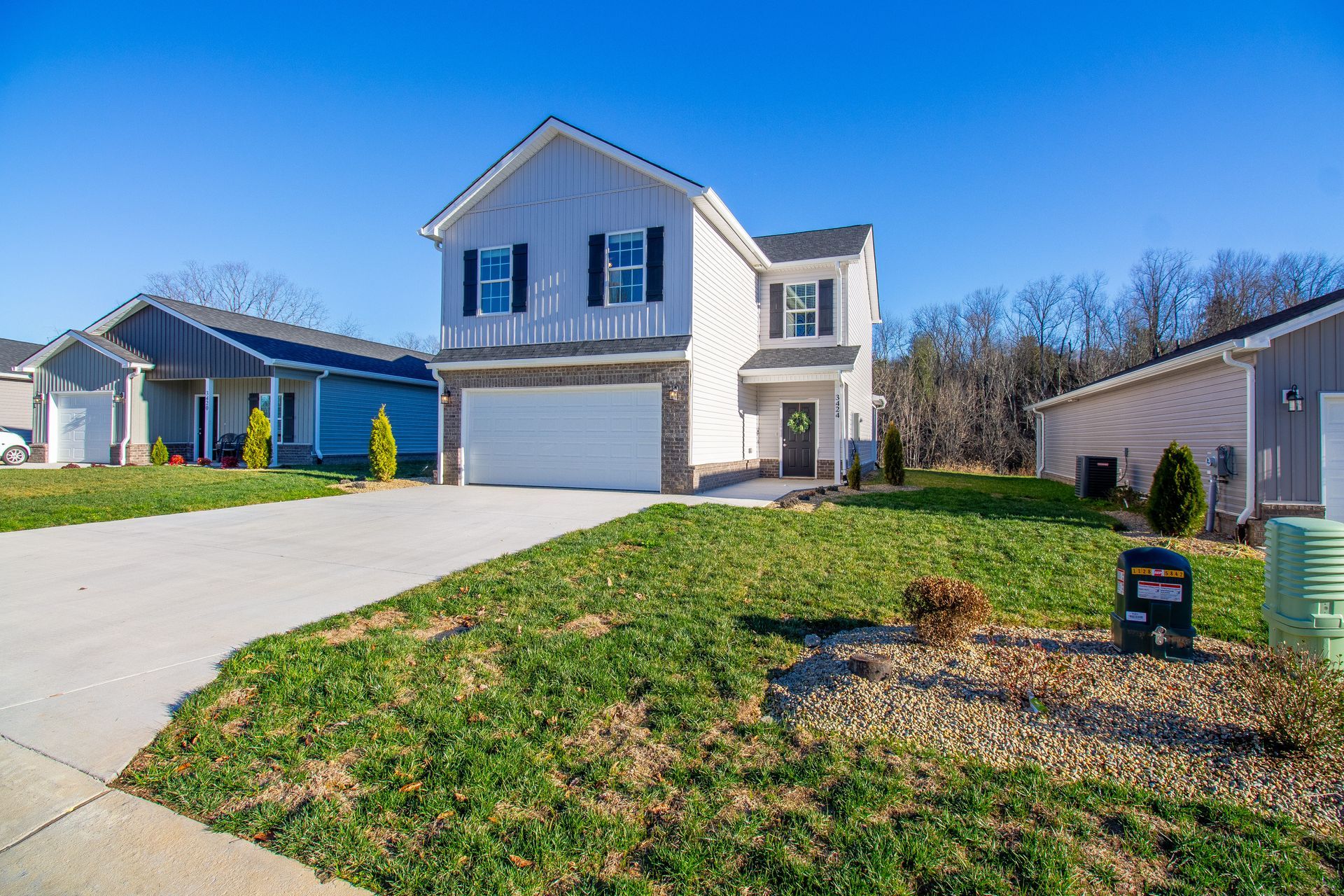 A large white house with a large driveway in a residential neighborhood.
