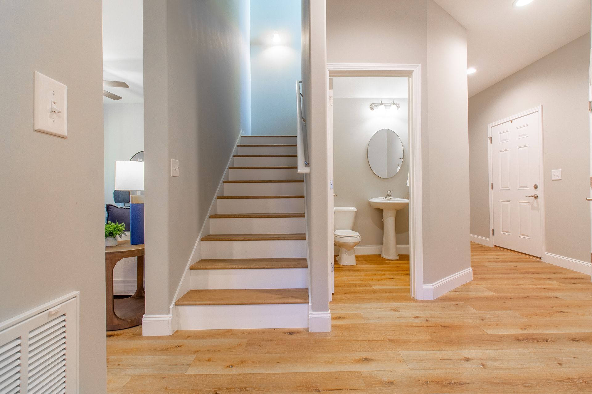 A hallway with stairs leading up to the second floor and a bathroom.