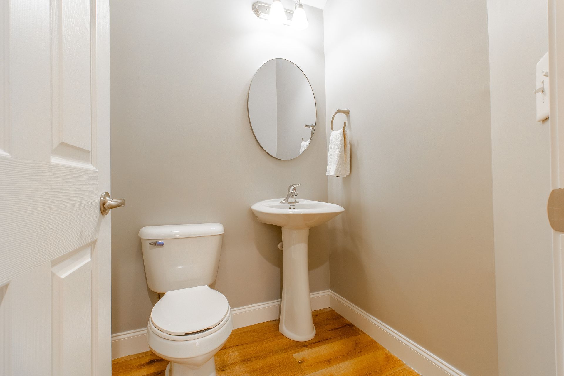 A bathroom with a toilet , sink and mirror.
