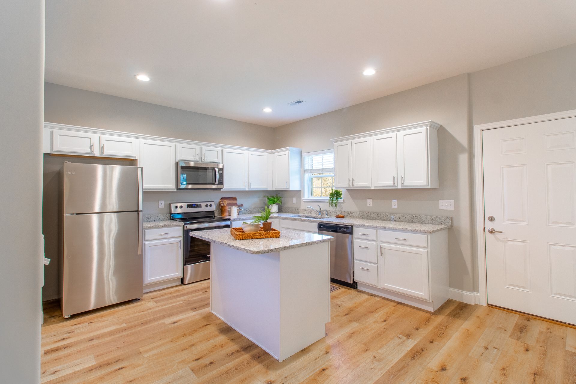 A kitchen with white cabinets , stainless steel appliances , and hardwood floors.