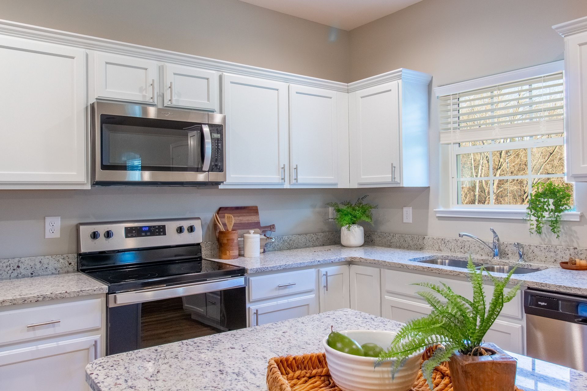 A kitchen with white cabinets , stainless steel appliances , granite counter tops and a stove.