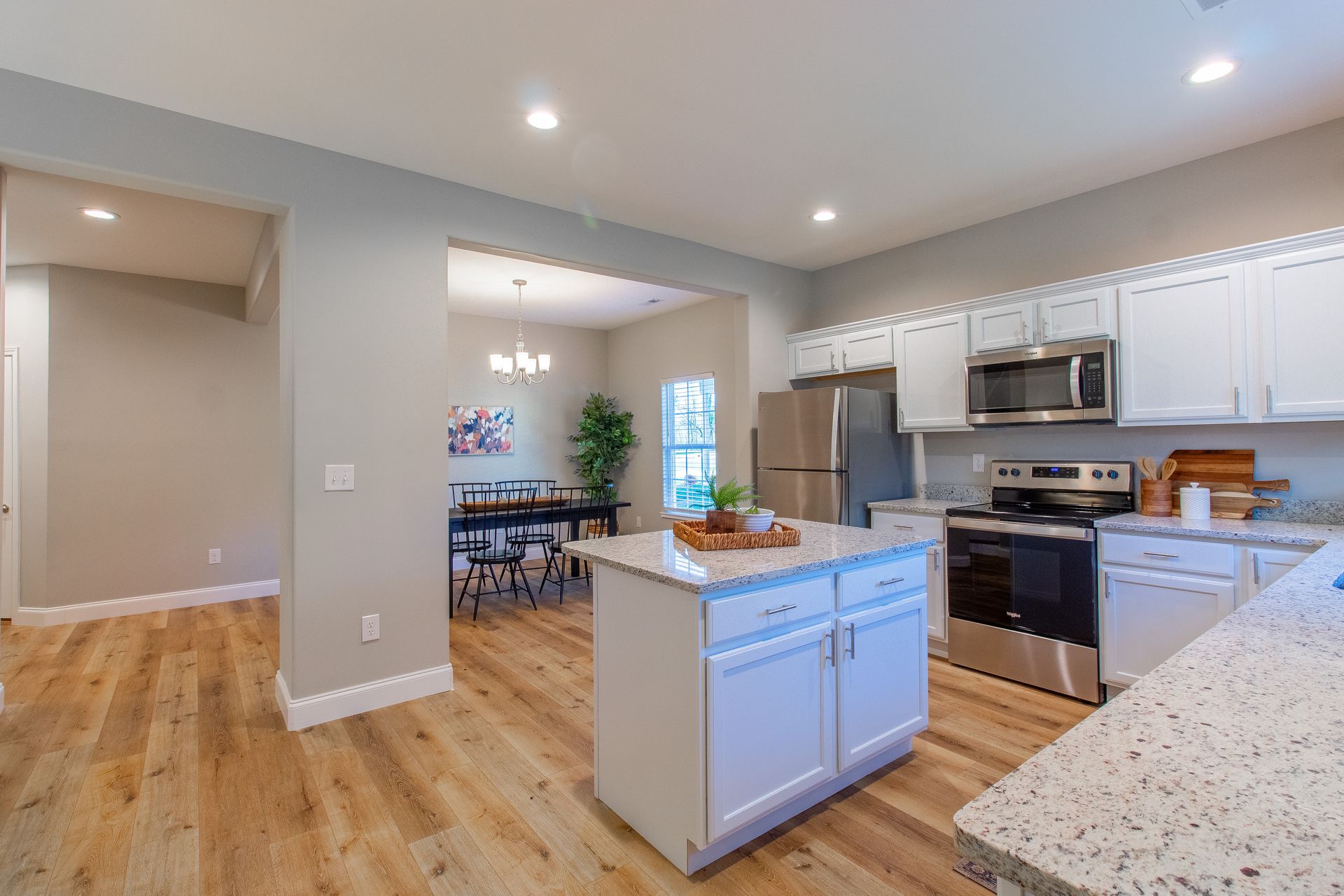 A kitchen with white cabinets , granite counter tops , stainless steel appliances and a large island.