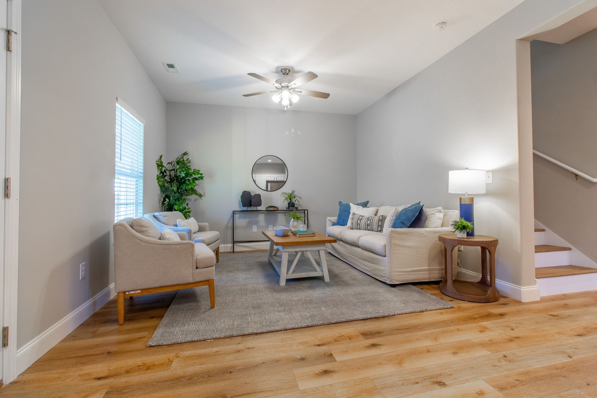 A living room with a couch , chair , coffee table and stairs.