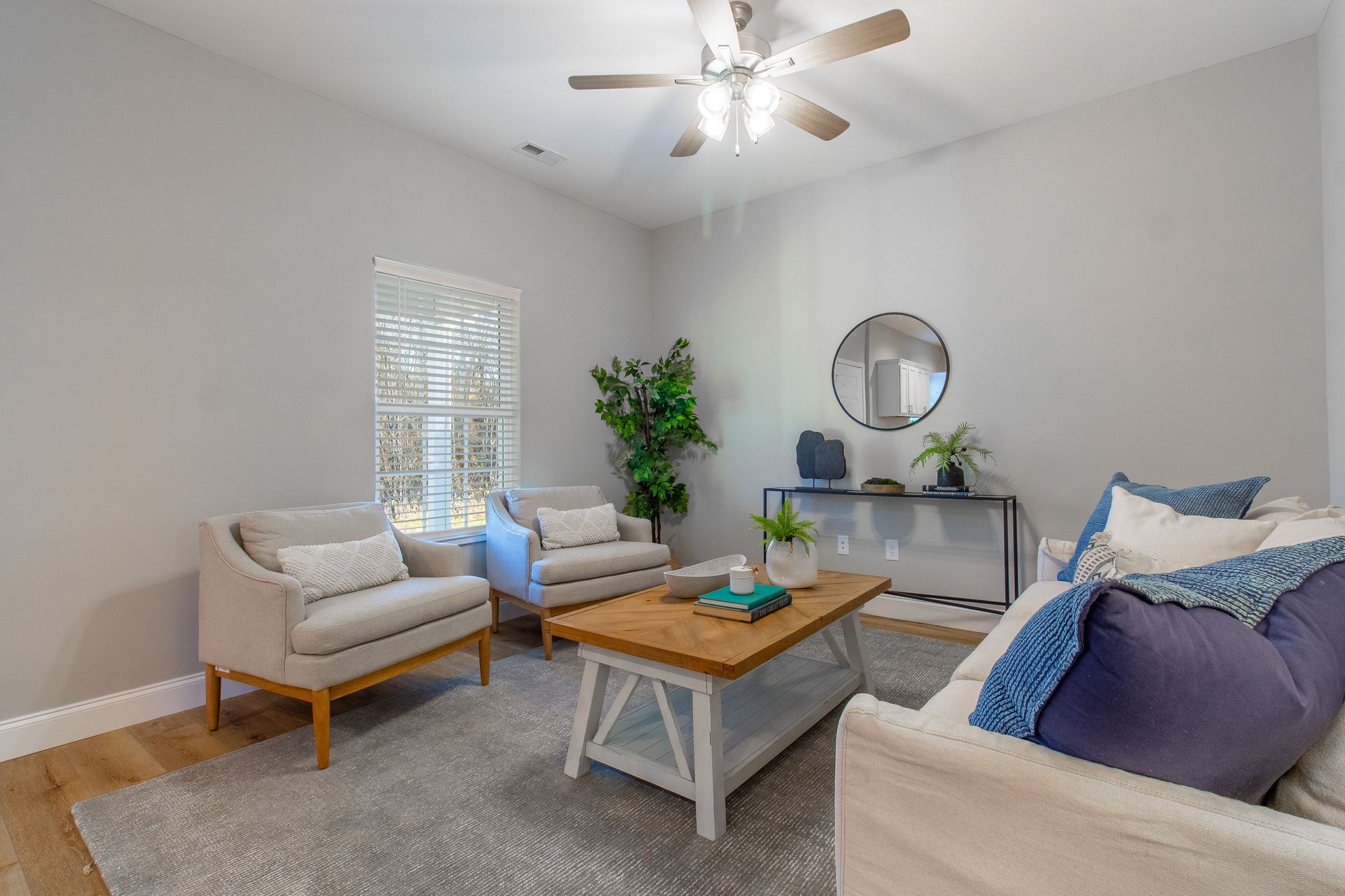 A living room with a couch , chairs , coffee table and ceiling fan.