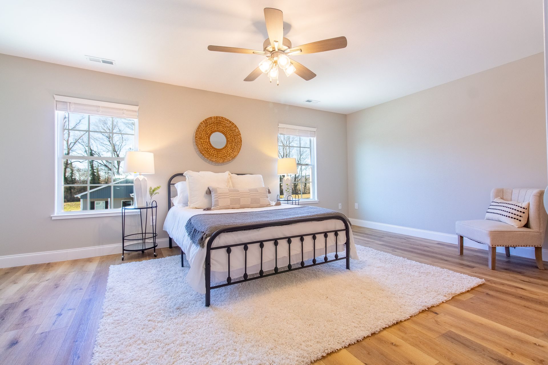 A bedroom with a bed , chair , rug and ceiling fan.