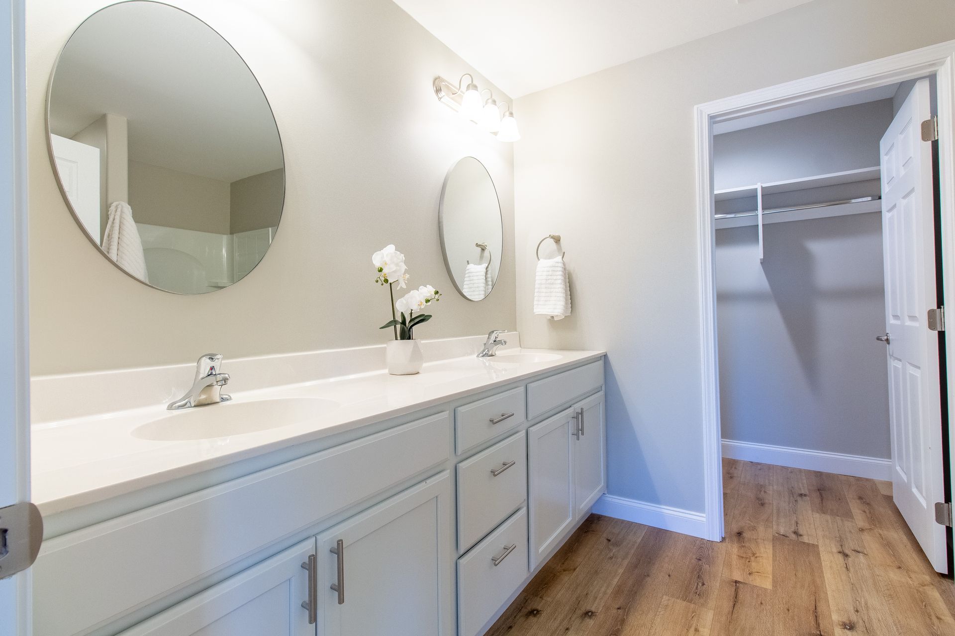 A bathroom with two sinks , a mirror and a walk in closet.