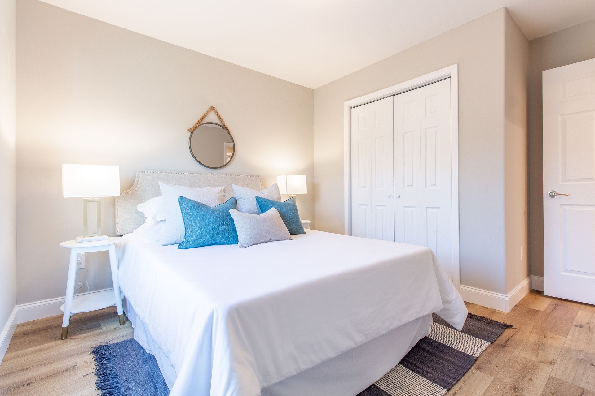 A bedroom with a bed , nightstand , mirror and rug.